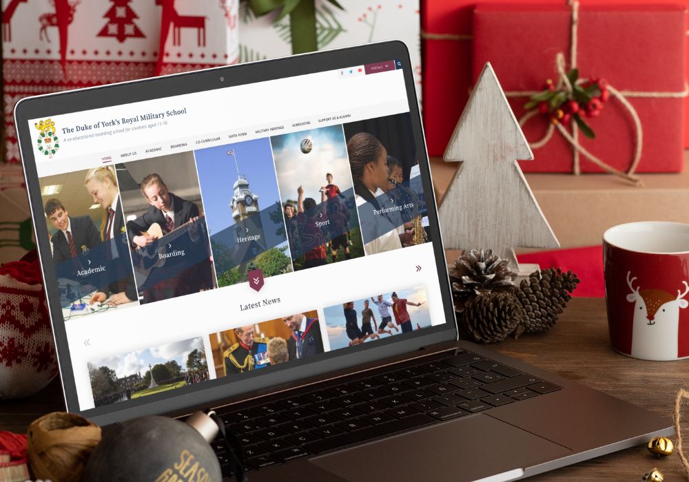 The Duke of York's Royal Military School website on a worktop surrounded by Christmas themed items